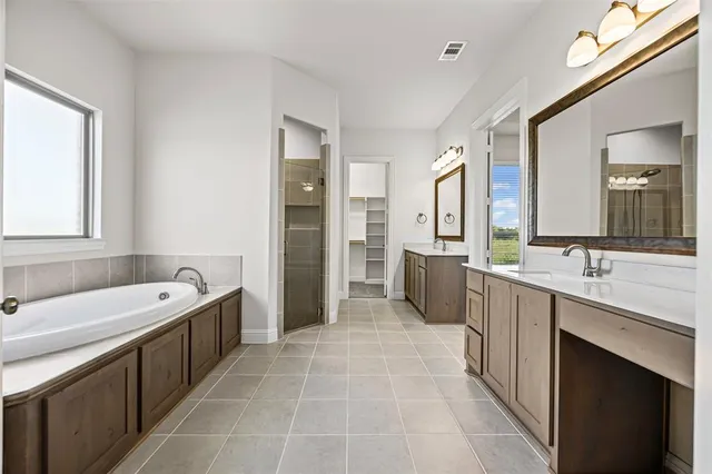 a large bathroom with a double vanity sink a mirror and a bathtub