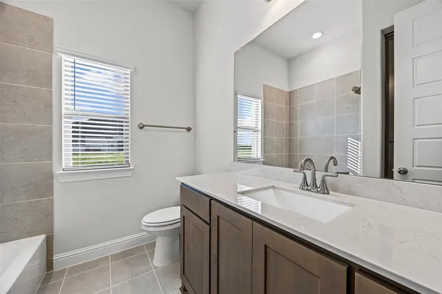 a bathroom with a granite countertop sink a toilet a mirror and shower
