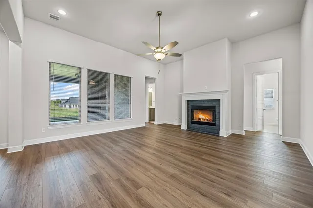 a view of an empty room with wooden floor fireplace and a window