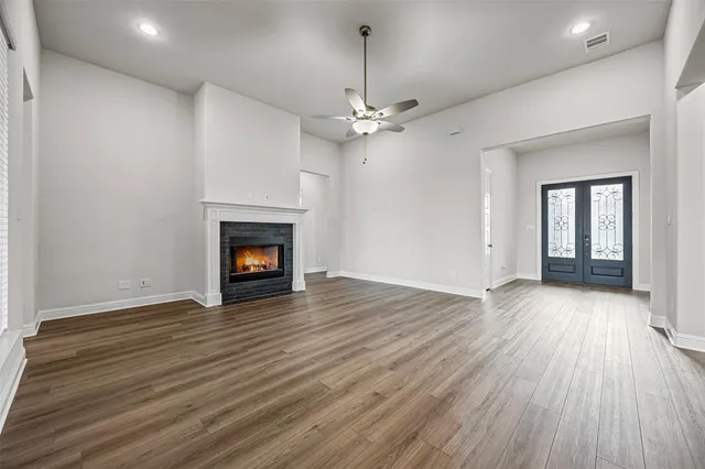 a view of an empty room with wooden floor fireplace and a window