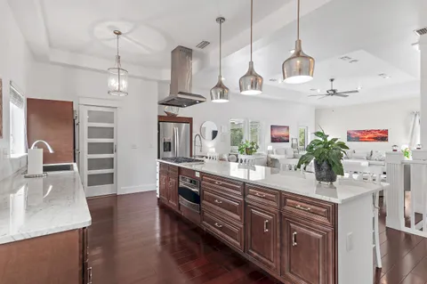 a kitchen with stainless steel appliances kitchen island granite countertop a sink a counter space and wooden floor