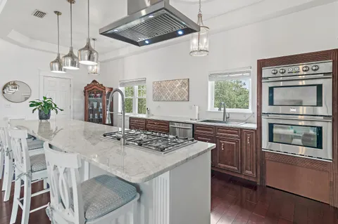 a kitchen with stainless steel appliances granite countertop a stove a microwave a dining table and chairs with wooden floor