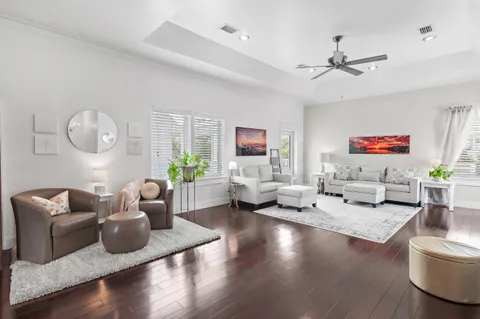 a living room with furniture kitchen view and a wooden floor