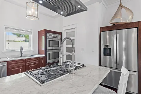 a kitchen with stainless steel appliances granite countertop a refrigerator a stove and a sink with wooden floor