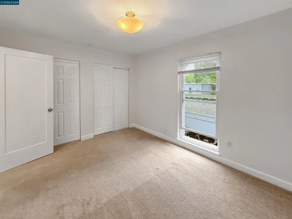 a view of an empty room with a window and dresser