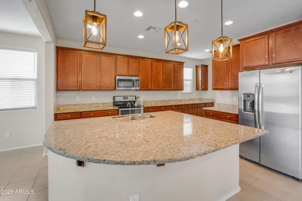 a kitchen with kitchen island granite countertop a sink a counter top space appliances and cabinets