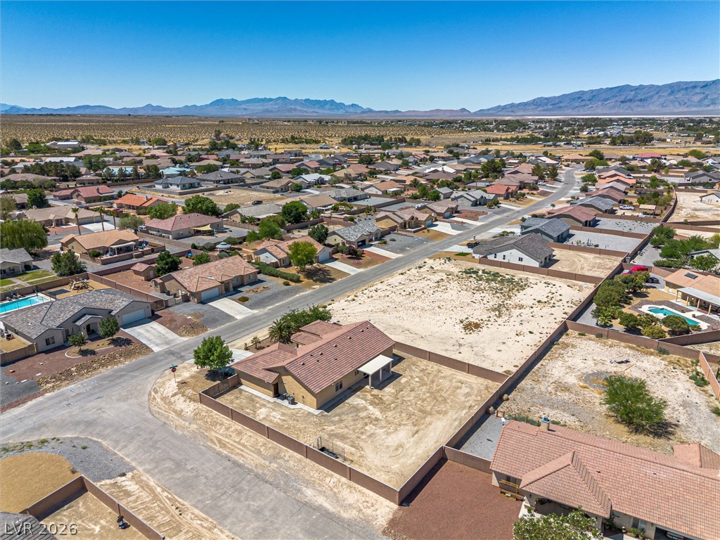 6720 Stubblefield Drive Pahrump, NV 89061 - Photo 39 of 51 An aerial perspective reveals a quiet suburban street nestled amidst distant mountain ranges and a vast desert landscape.