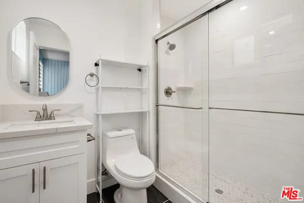 a bathroom with a granite countertop shower a sink and a mirror