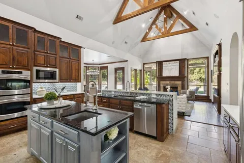a kitchen with stainless steel appliances granite countertop a stove and a view of living room