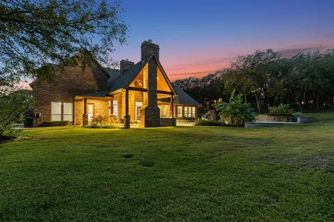 a view of a big house with a big yard and large trees