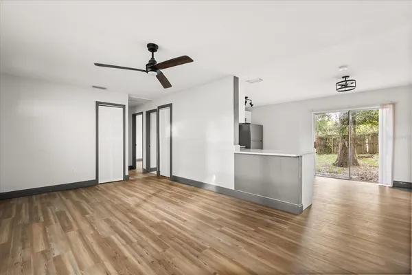 a view of a kitchen with wooden floor a ceiling fan and windows