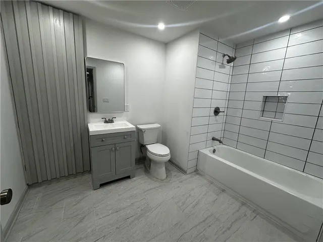 a bathroom with a toilet a sink a mirror a bathtub and shower