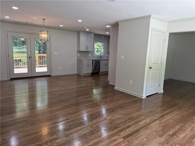 an empty room with wooden floor and kitchen view