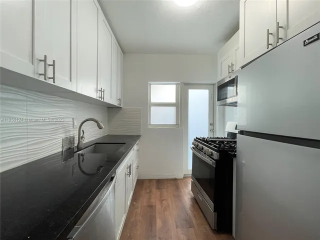a kitchen with granite countertop a refrigerator stove and sink