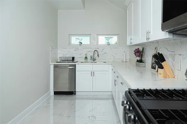 a large white kitchen with a stove top oven sink and cabinets