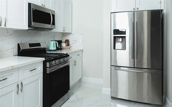 a kitchen with stainless steel appliances granite countertop a refrigerator a stove a sink and a microwave