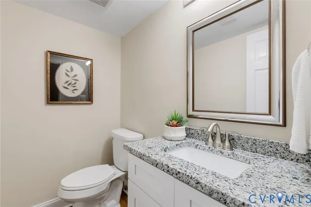 a bathroom with a granite countertop toilet a sink and a mirror