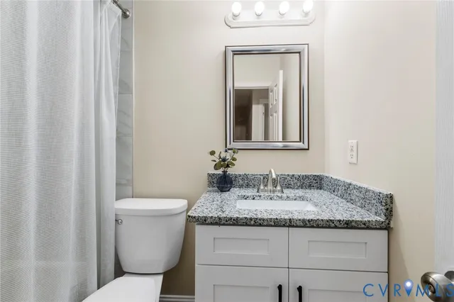 a bathroom with a granite countertop sink toilet and mirror