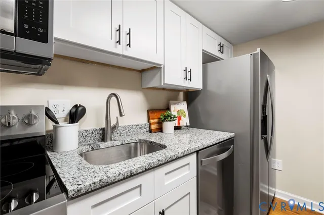 a kitchen with stainless steel appliances granite countertop a sink refrigerator and cabinets