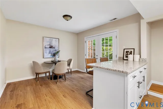 a dining room with kitchen island stainless steel appliances furniture a large window and wooden floor