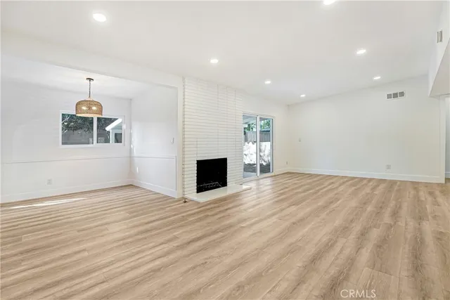 an empty room with wooden floor and fireplace