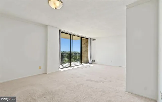 a view of an empty room with wooden floor and windows