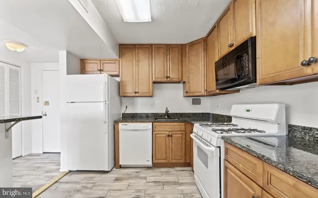 a kitchen with stainless steel appliances granite countertop a refrigerator stove a sink dishwasher and microwave oven