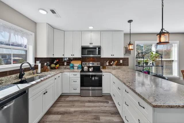 a large kitchen with granite countertop a stove top oven a sink a counter space and cabinets