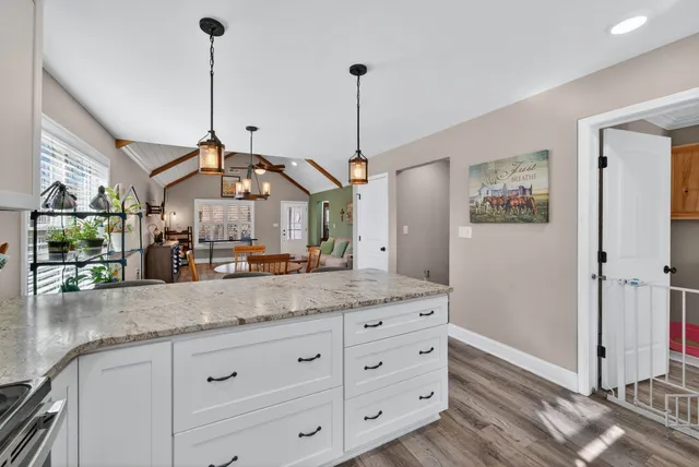 a dining hall with granite countertop white cabinets and a wooden floor