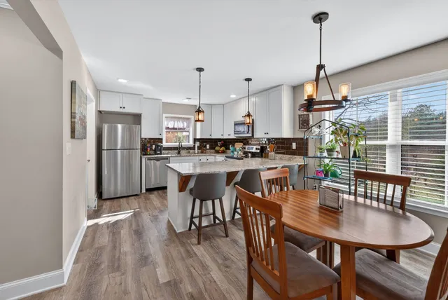 a view of a dining room and livingroom with furniture wooden floor a chandelier