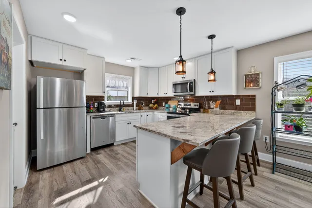 a kitchen with stainless steel appliances granite countertop a refrigerator a sink dishwasher a stove and a refrigerator