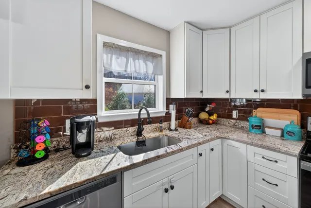 a kitchen with stainless steel appliances granite countertop a sink dishwasher and cabinets with wooden floor