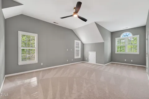 an empty room with wooden floor chandelier fan and windows