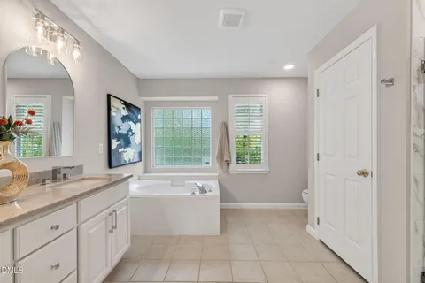 an empty room with wooden floor chandelier fan and windows