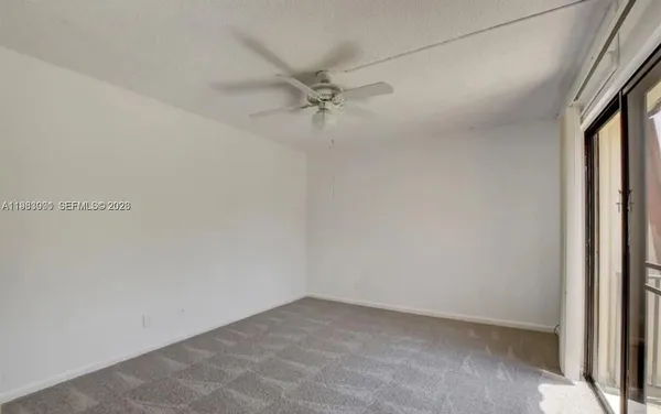 an empty room with a ceiling fan and carpet