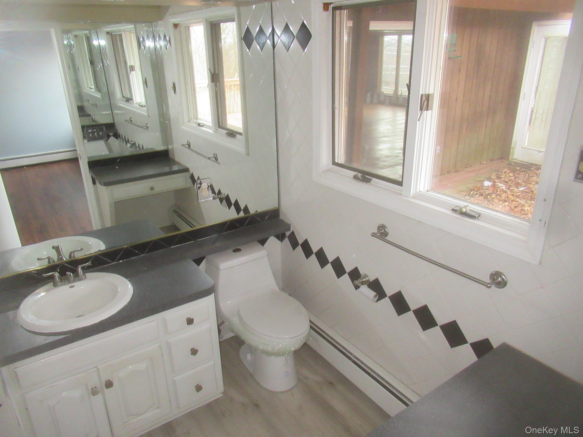 64 Hillside View Road Mahopac, NY 10541 - Photo 18 of 25 Half bathroom with light wood-style floors, vanity, a baseboard heating unit, and healthy amount of natural light