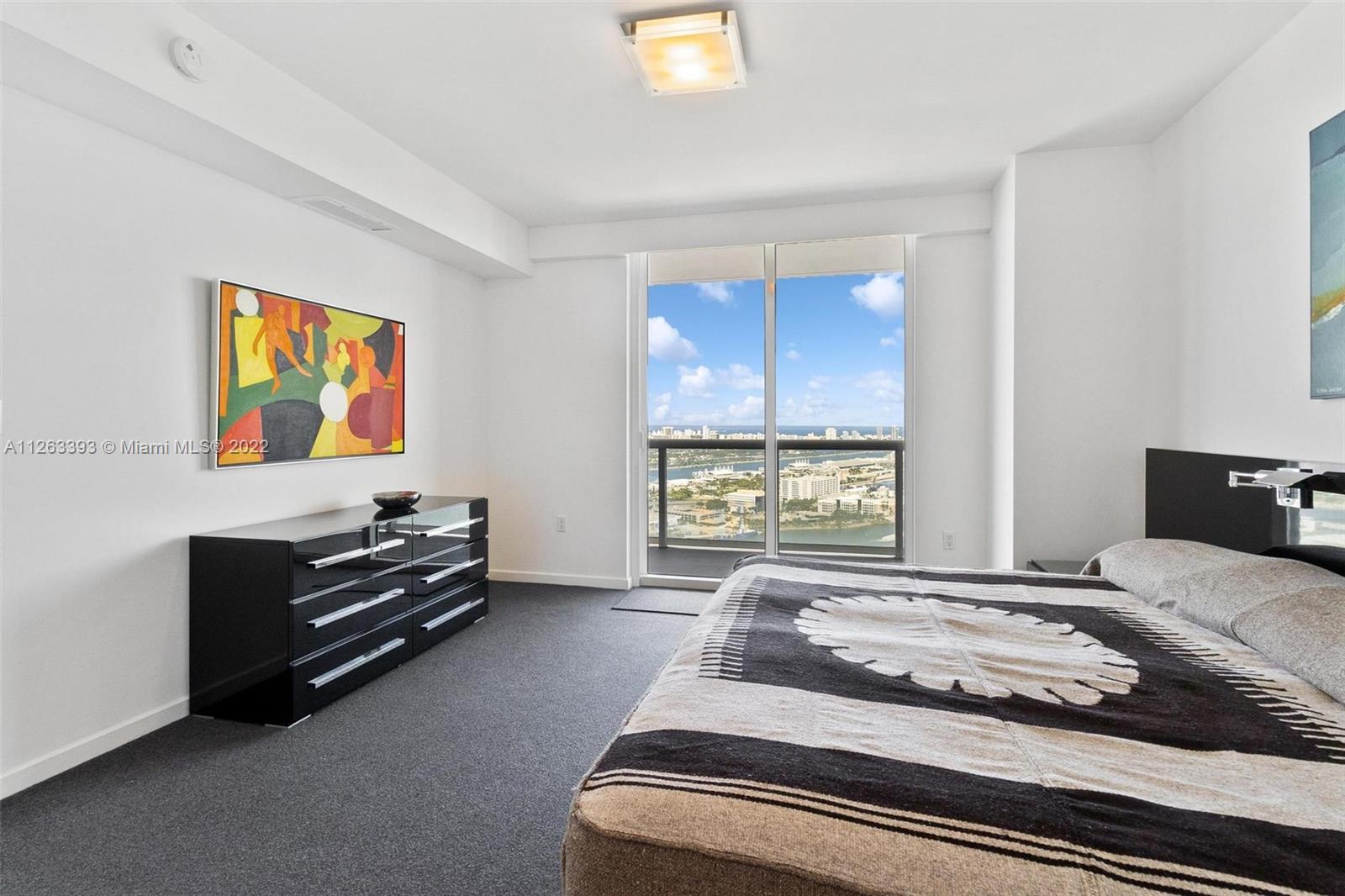 50 Biscayne Boulevard, Unit 4802 Miami, FL 33132 - Photo 15 of 33 a bedroom with a bed and dresser next to a window