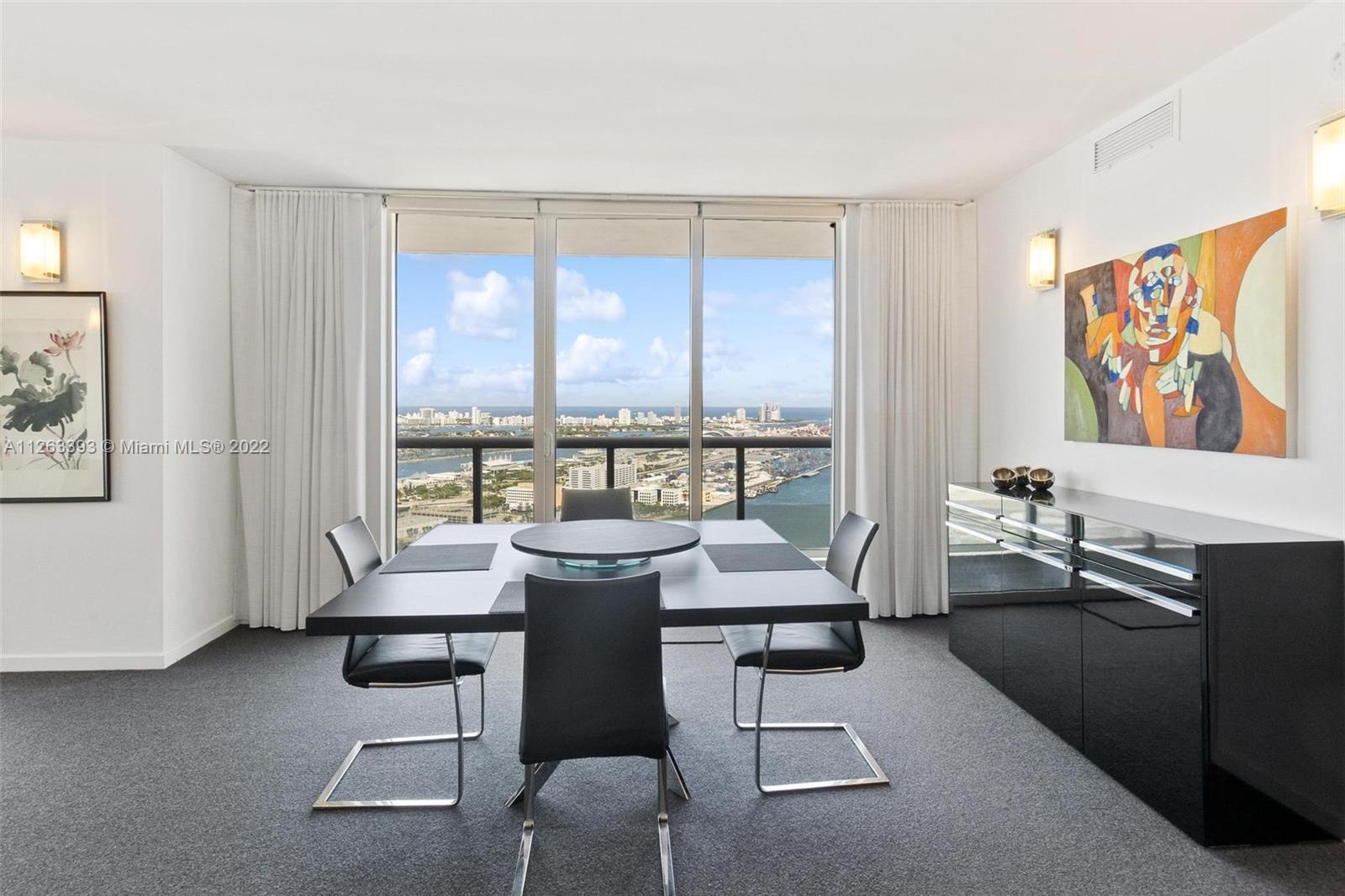 50 Biscayne Boulevard, Unit 4802 Miami, FL 33132 - Photo 2 of 33 a living room with furniture a large window and a flat screen tv