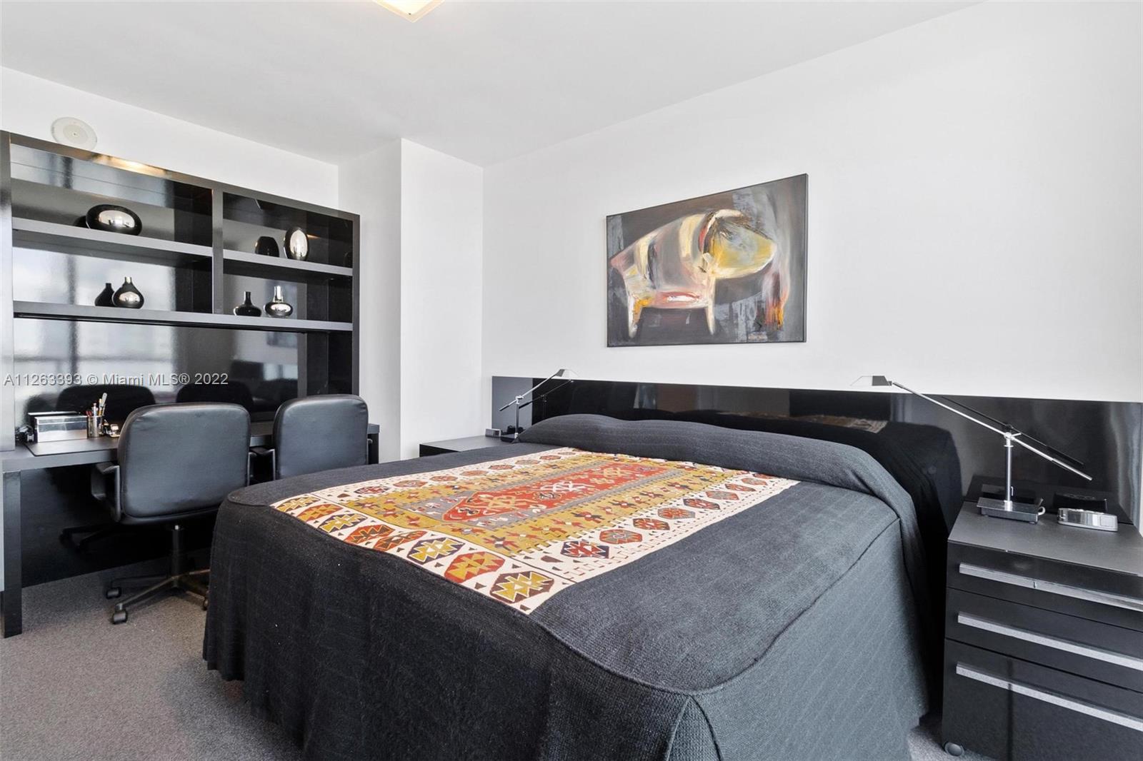 50 Biscayne Boulevard, Unit 4802 Miami, FL 33132 - Photo 22 of 33 a bedroom with a bed and a bookshelf