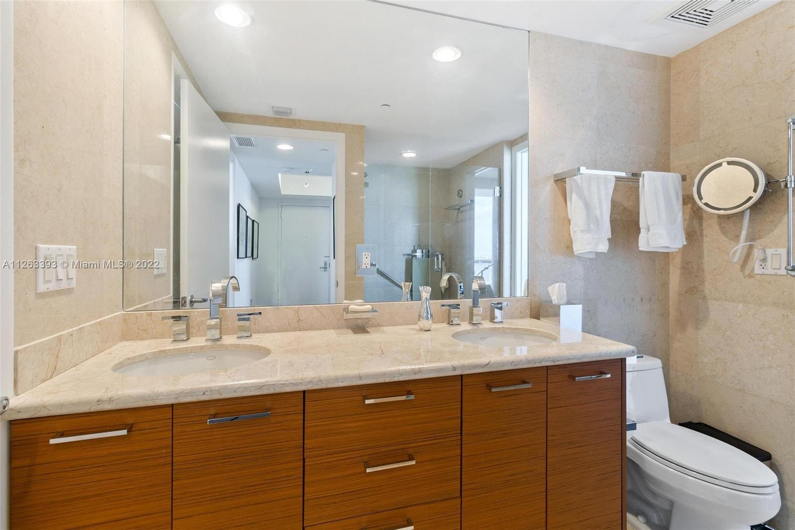 50 Biscayne Boulevard, Unit 4802 Miami, FL 33132 - Photo 24 of 33 a bathroom with a granite countertop sink a toilet and a mirror