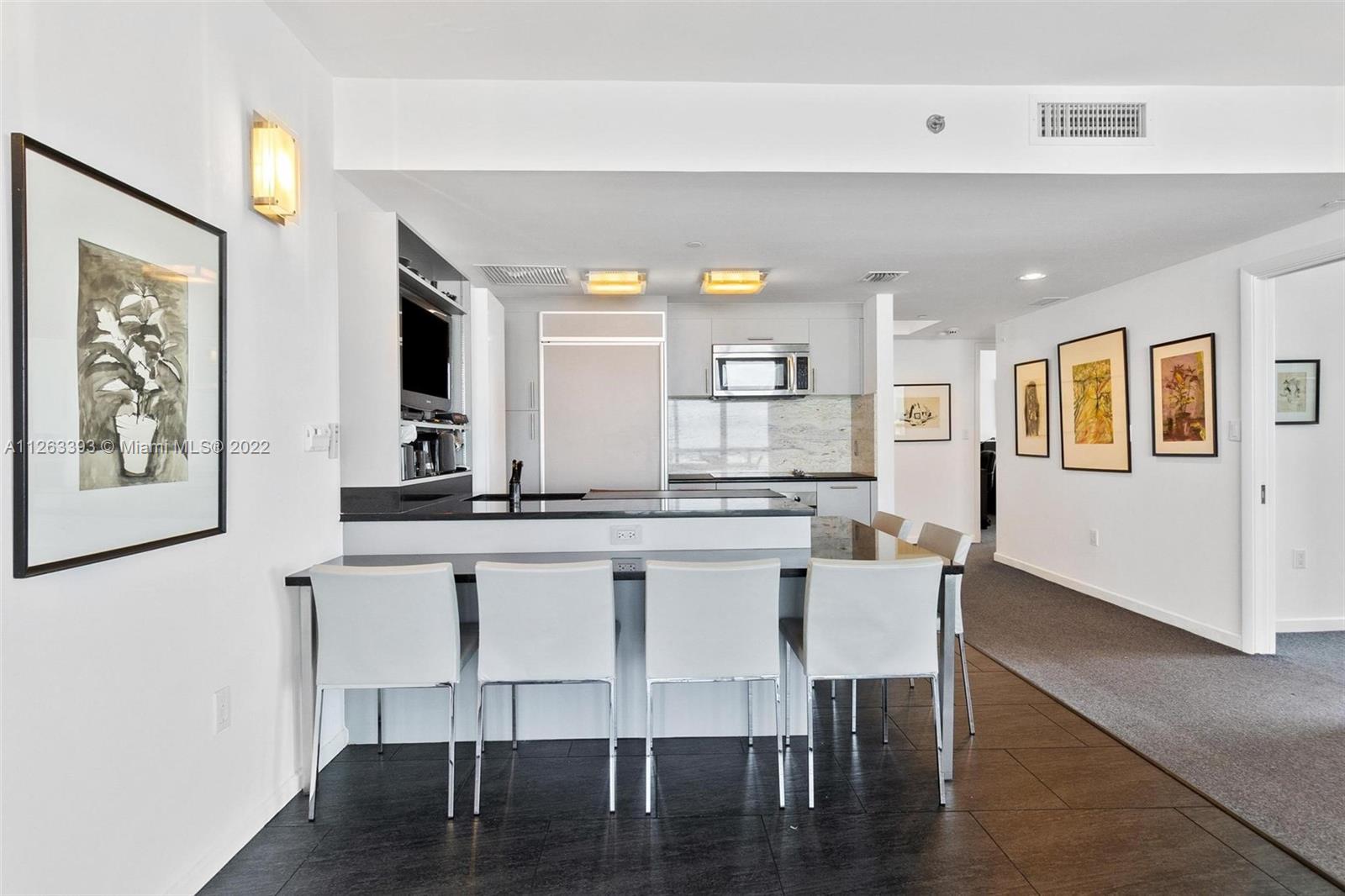 50 Biscayne Boulevard, Unit 4802 Miami, FL 33132 - Photo 3 of 33 a kitchen with stainless steel appliances granite countertop a dining table chairs and a refrigerator