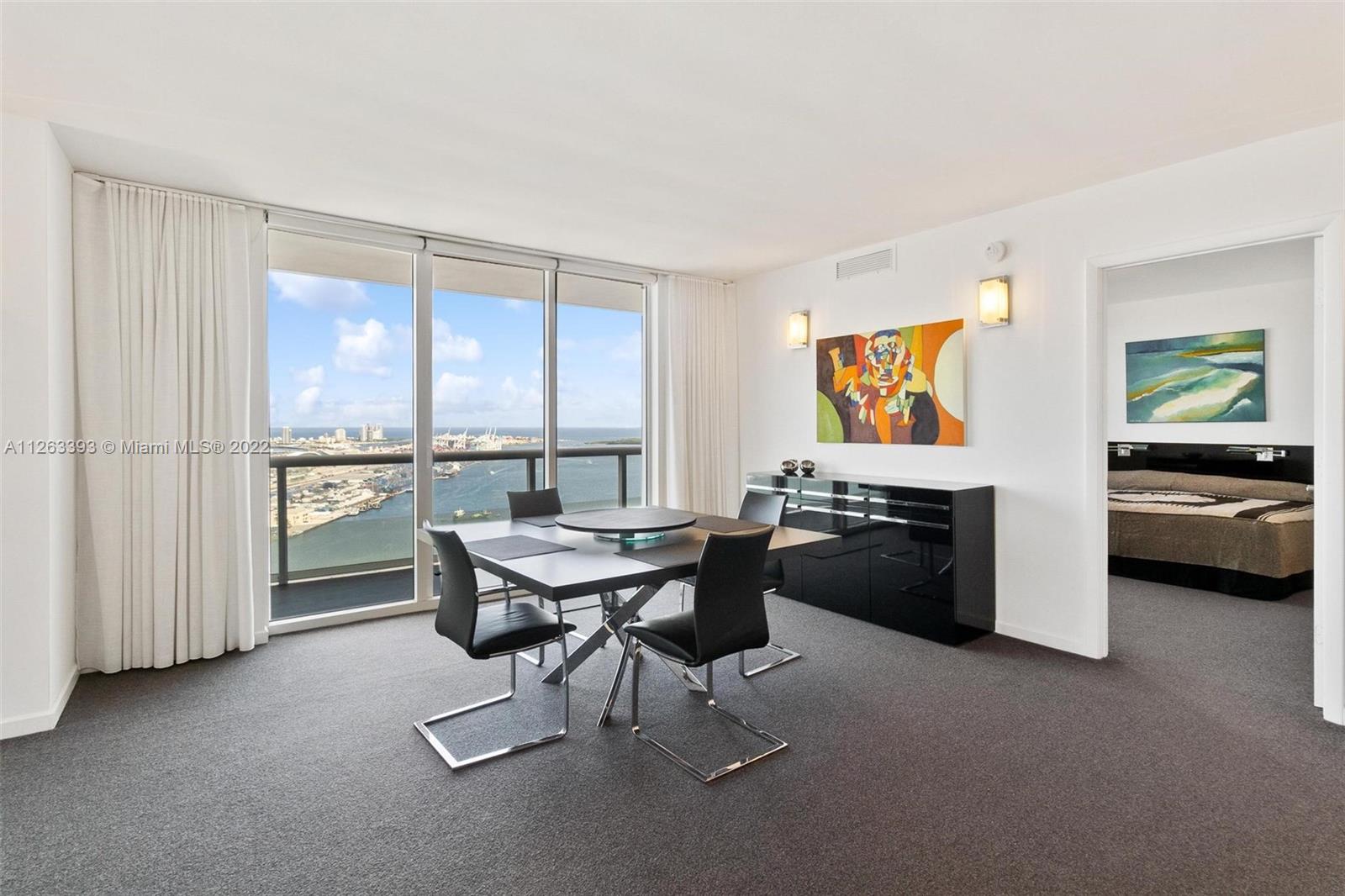 50 Biscayne Boulevard, Unit 4802 Miami, FL 33132 - Photo 5 of 33 a living room with furniture a large window and kitchen view