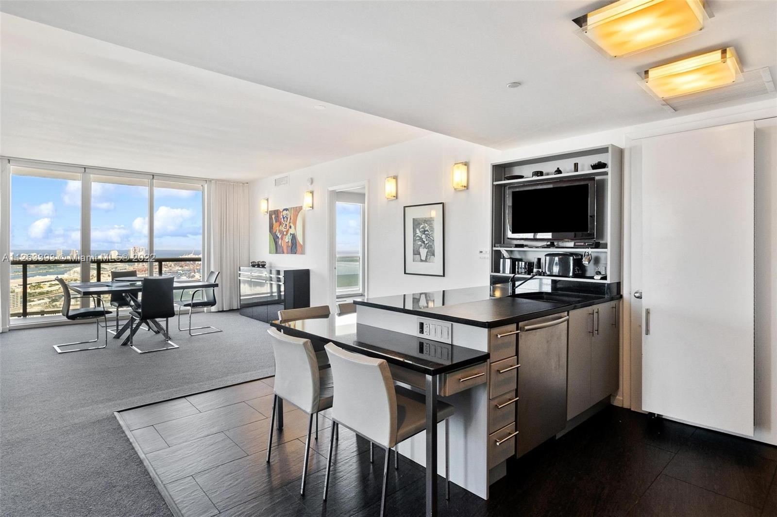 50 Biscayne Boulevard, Unit 4802 Miami, FL 33132 - Photo 9 of 33 a kitchen with sink cabinets and dining table