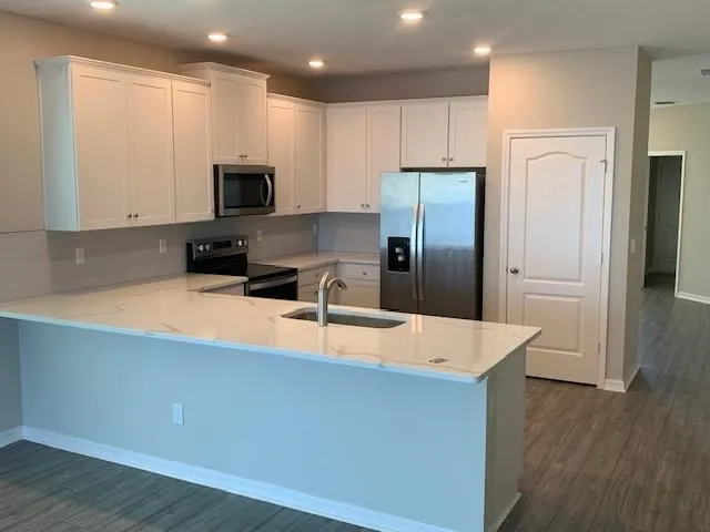 a large kitchen with stainless steel appliances a large counter top and wooden floors