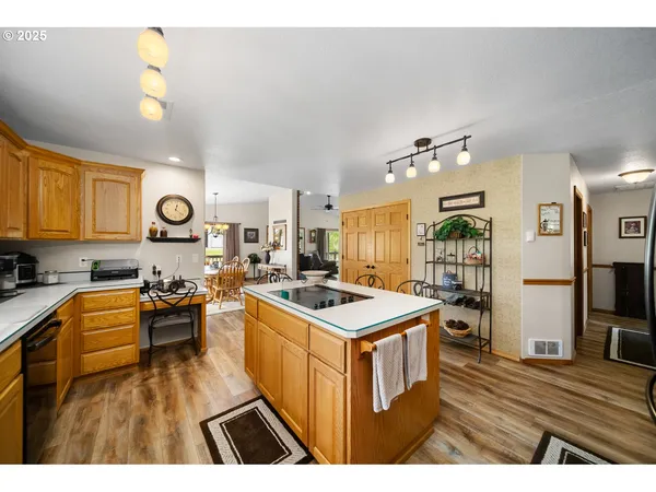 a open kitchen with kitchen island a stove a sink dishwasher and a dining table with wooden floor