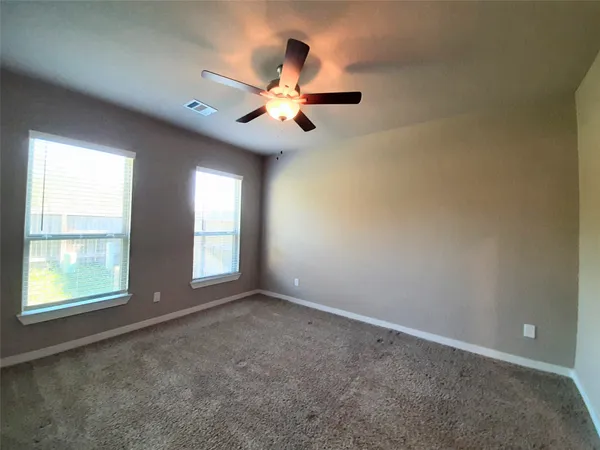 an empty room with windows and fan