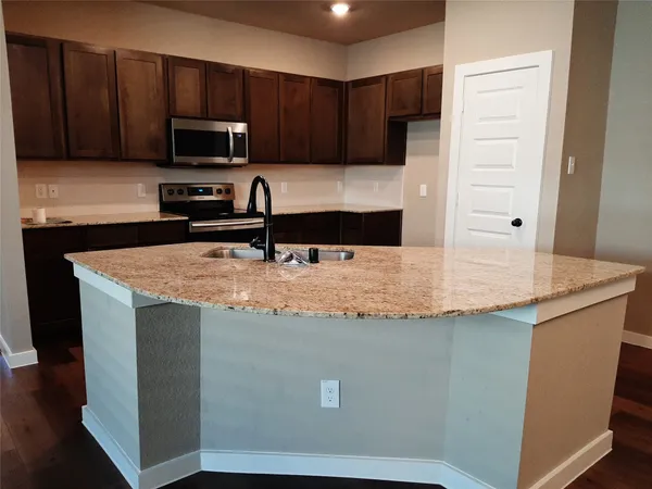 a kitchen with kitchen island a sink a stove a refrigerator and cabinets