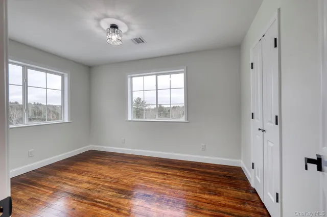 a view of empty room with wooden floor and fan