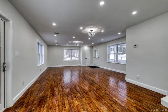 a view of an empty room and window and wooden floor