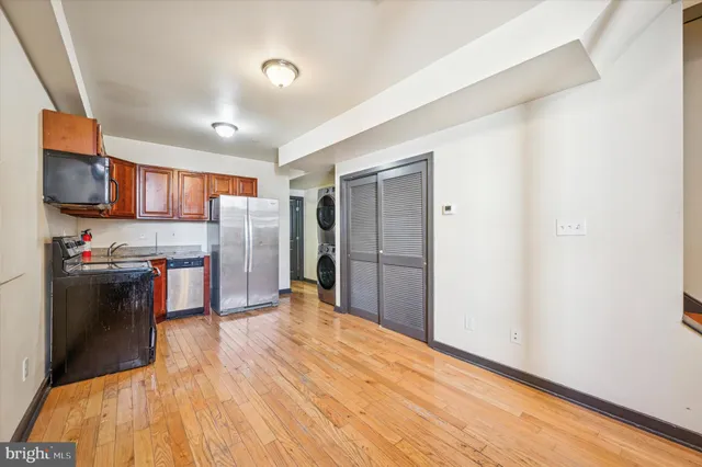 a kitchen with stainless steel appliances a refrigerator and a wooden floor